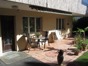 A patio with a table and chairs, a potted plant, and a door. - Frei, (Bad Ragaz), by Interhome (Bad Ragaz)