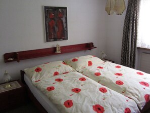 A bedroom with a bed, a nightstand, a wall-mounted shelf, and a painting. - Frei, (Bad Ragaz), by Interhome (Bad Ragaz)