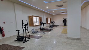 Un gimnasio con equipo de ejercicio, un extintor y una ventana con marco de madera.