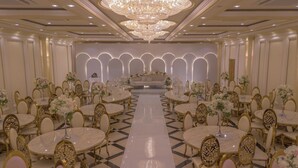 Un salón de banquetes con mesas redondas, sillas y un arreglo floral central.