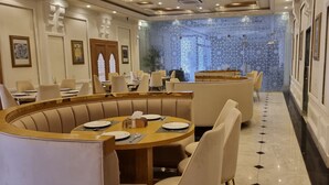 Un restaurante con mesas redondas, asientos tipo banqueta acolchados y una pared con diseño.
