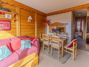 A cozy wooden interior with a red sofa, wooden dining table, and chairs. - Spacious apartment, covered parking - 9 guests (Belle Plagne)