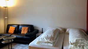 Una habitación con una cama, un sofá de cuero negro, una mesita redonda y una lámpara.