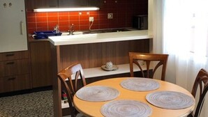 Una cocina con armarios de madera, una mesa redonda con individuales y una lámpara colgante.