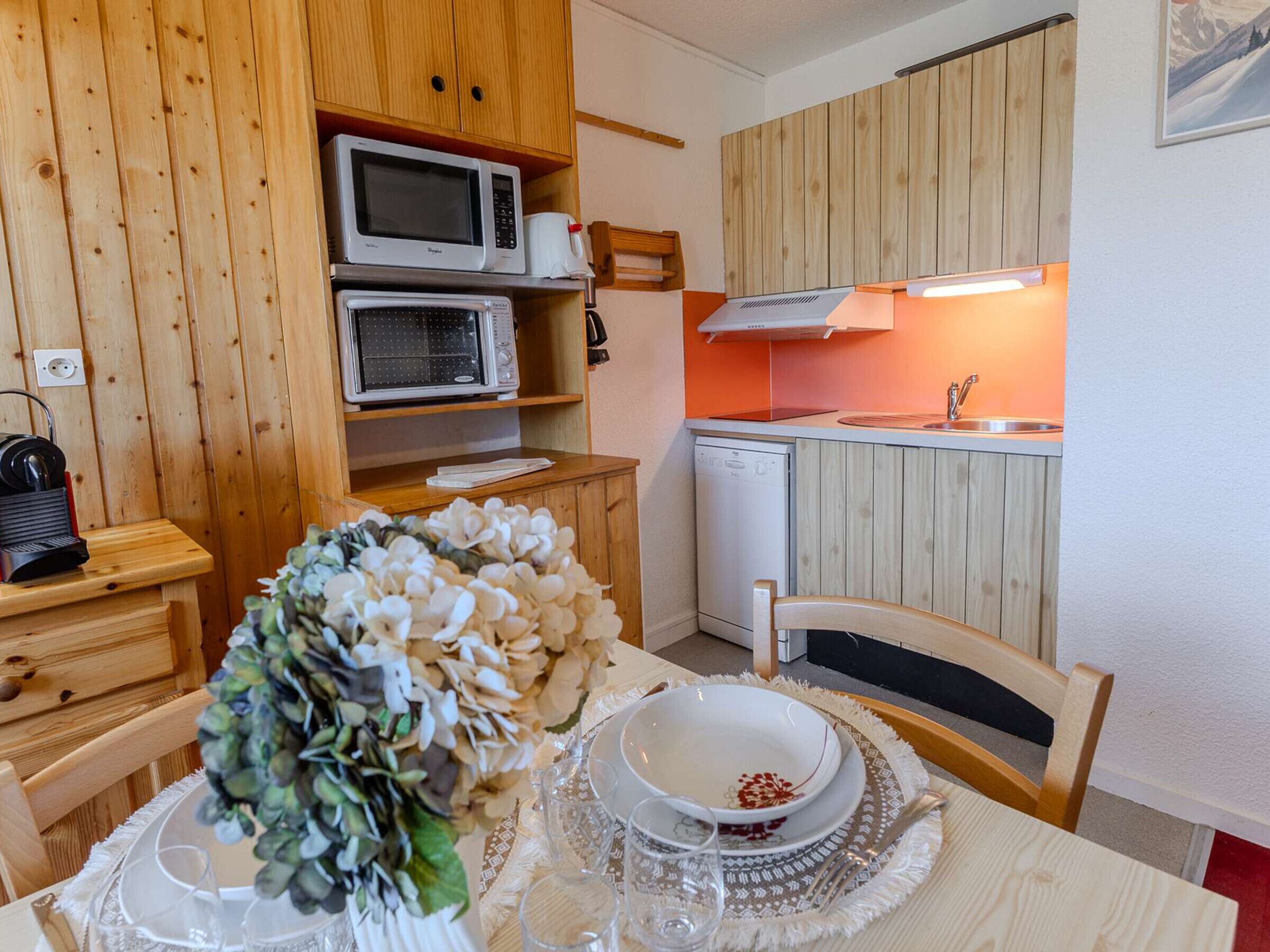 Uma cozinha compacta com armários de madeira, micro-ondas, torradeira e máquina de lavar louça.