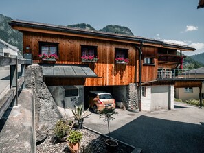 A wooden house with a car parked in the driveway, surrounded by potted plants. - Casa Marie, (Malans), by Interhome (Malans)
