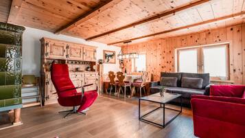 A wooden interior with a dining area, sofa, and red armchair.