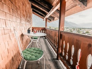 Un balcón de madera con una mesa y sillas, con vistas a un paisaje montañoso.