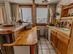 Eine Küche mit Holzschränken, einer eingebauten Mikrowelle, einem Spülbecken und einem Fenster mit Blick auf eine verschneite Landschaft.