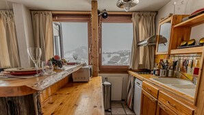 Una cucina con mobili in legno, forno a microonde integrato, lavandino e finestra con vista su un paesaggio innevato.