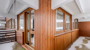 Una stanza con pannelli in legno, ampie finestre e soffitto spiovente.