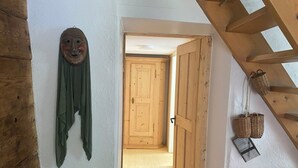 A wooden door leading to a hallway with a wooden ceiling and a wall-mounted mask. - Geelerhaus, (Berschis), by Interhome (Walenstadt)