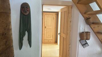 Une porte en bois qui donne sur un couloir doté d’un plafond en bois et d’un masque fixé au mur.