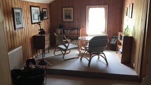 A cozy room with wooden walls, a bookshelf, a rocking chair, a small table, and a radiator. - Geelerhaus, (Berschis), by Interhome (Walenstadt)