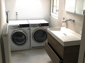 A compact laundry area with two front-loading washing machines and a sink.