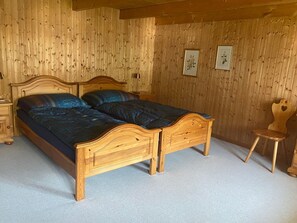 A wooden bed with a headboard, a bedside table, and a chair in a room with wooden walls.