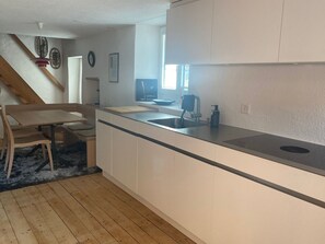 A modern kitchen with a wooden dining table, a built-in sink, and a window providing natural light.