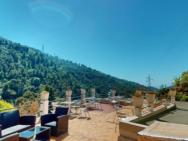 An outdoor terrace with tables and chairs, overlooking a forested hillside. - Air-conditioned room, mountain view (MONTI (06500))