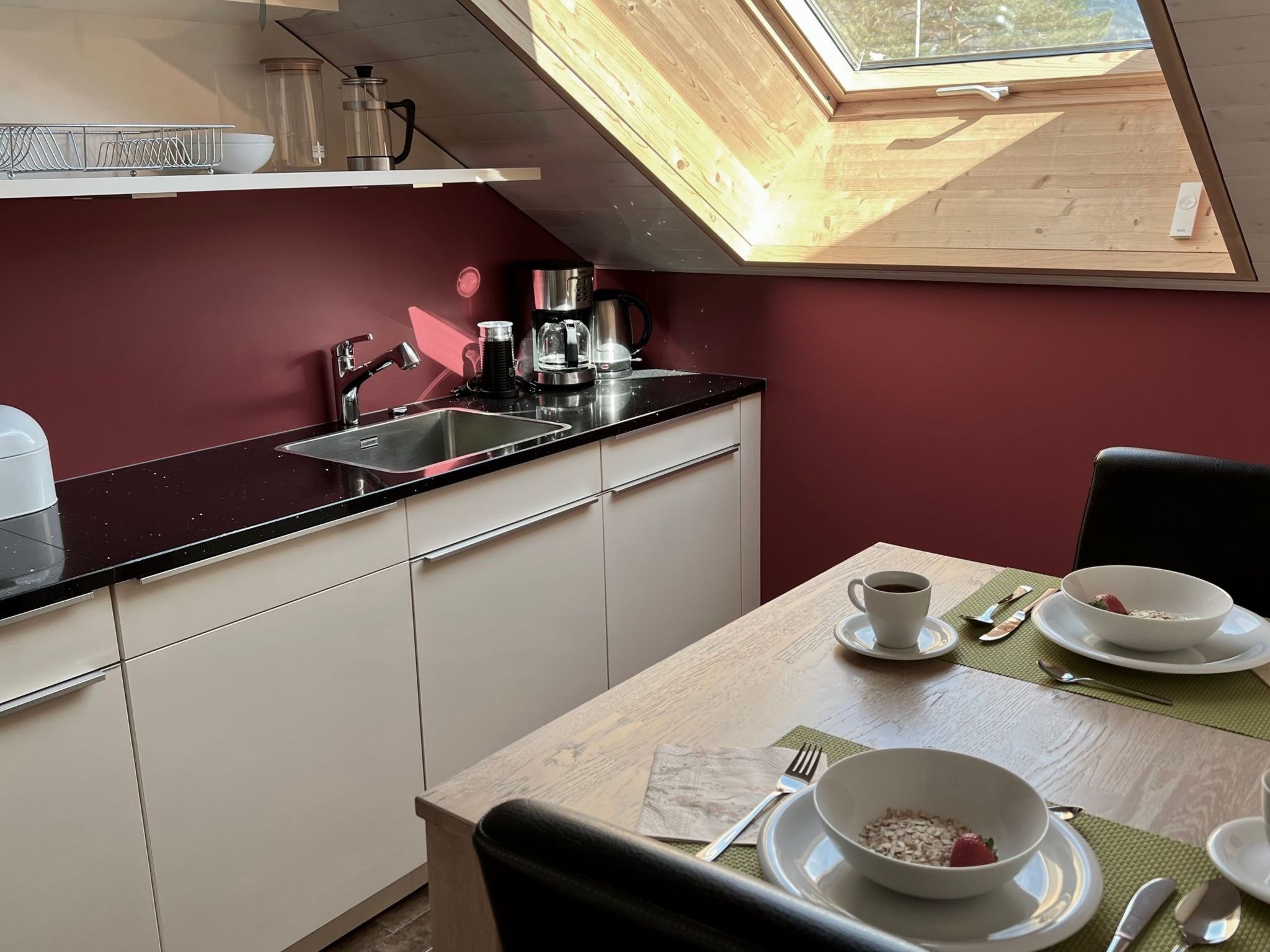 A compact kitchen with a skylight, a sink, and a dining area with a table set for two.