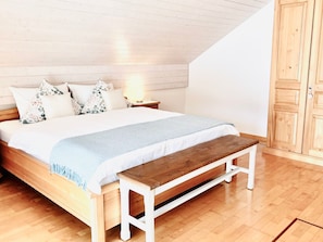 A bedroom with a wooden bed, white bedding, a bench, and a wooden wardrobe. - Chriesilöser, (Bad Ragaz), by Interhome (Bad Ragaz)