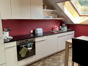 A modern kitchen with a red wall, a black countertop, and a skylight. - Chriesilöser, (Bad Ragaz), by Interhome (Bad Ragaz)