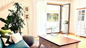 A modern living room with a sofa, a coffee table, a large plant, and a view through a glass door. - Chriesilöser, (Bad Ragaz), by Interhome (Bad Ragaz)