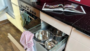 A kitchen with a modern stove, a drawer with pots, and a cookbook on the counter. - Chriesilöser, (Bad Ragaz), by Interhome (Bad Ragaz)