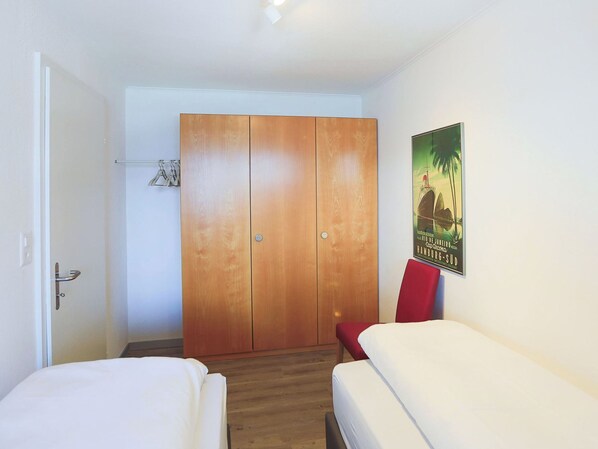 Habitación de hotel con un armario de madera, una cama, una silla roja y un cartel en la pared.