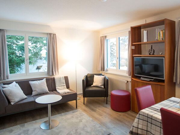 A modern living room with a sofa, armchair, TV, and a small table.