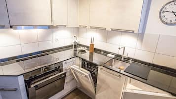 Cozinha moderna com armários brancos, pia de aço inoxidável e forno embutido.