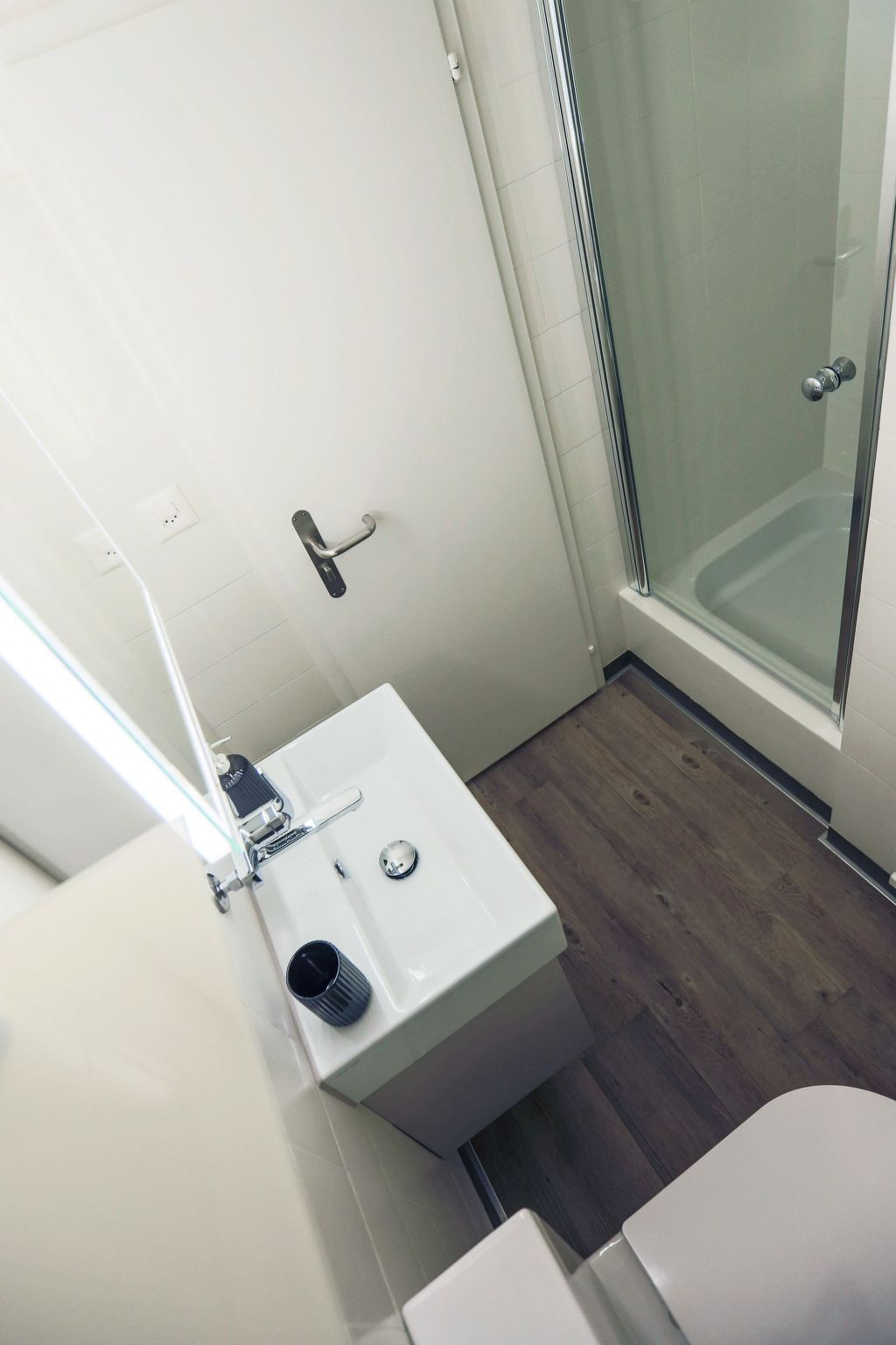 A bathroom with a white sink, a toilet, and a glass shower enclosure.