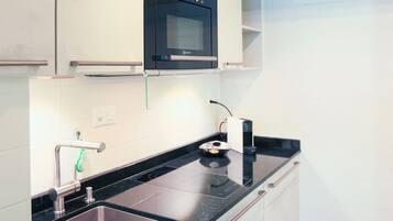 Una cocina moderna con horno empotrado, pileta de acero inoxidable y muebles de cocina blancos.