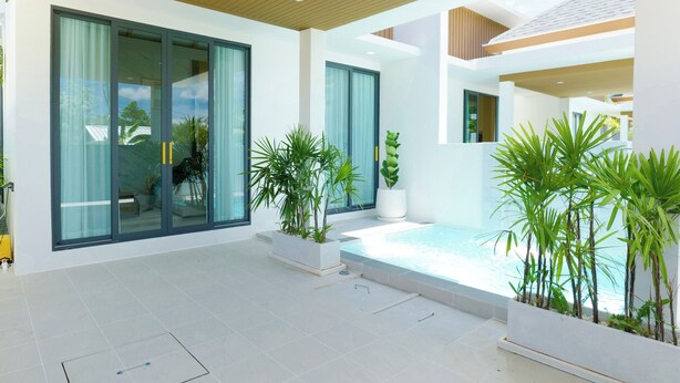 Ein modernes Haus mit großen Schiebeglastüren, einem Swimmingpool und Topfpflanzen.