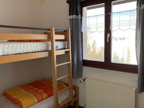 A bunk bed room with a window and a radiator.
