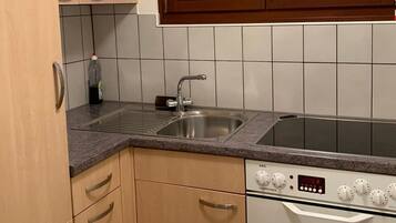 Eine Küche mit einer Edelstahl-Spüle, einem eingebauten Backofen und einem Fenster über der Spüle.