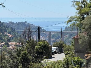 A coastal road with a bridge in the distance, surrounded by greenery and residential buildings. - Double room with air conditioning, mountain view (MONTI (06500))