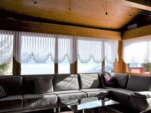 A cozy living room with a sofa, curtains, and a view of the outdoors.