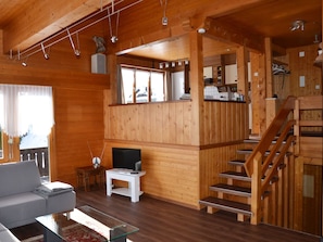 A wooden interior with a sofa, TV, and staircase. - Chalet am Tobelbach, (Flumserberg Tannenheim), by Interhome (Flumserberg Tannenheim)