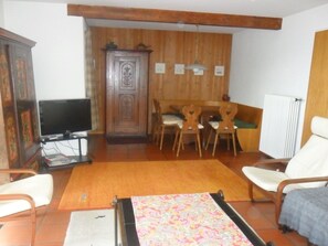 A living room with a television, wooden furniture, a patterned rug, and a radiator.