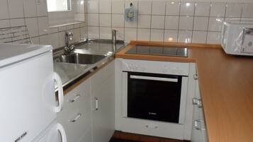 Eine kompakte Küche mit Backofen, Spüle und Arbeitsplatte.