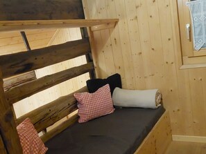 A wooden bunk bed with a mattress and pillows.