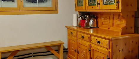 Ein Holzkabinett mit Glastüren, eine Bank und ein kleiner Mülleimer.