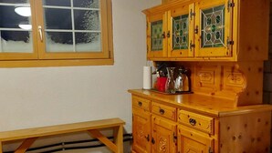 A wooden cabinet with glass doors, a bench, and a window with frosted glass. - Chrüterhütte, (Flumserberg Tannenboden), by Interhome (Flumserberg Tannenheim)
