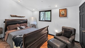 A bedroom with a large bed, a chair, a painting, and a window. - Woodland Home Near The Gorge - Private Deck 1 Bedroom Home (Washougal)