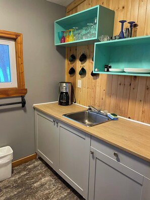 Eine Küche mit einer Holzausziehtafel, einem Spülbecken und einer Kaffeemaschine.
