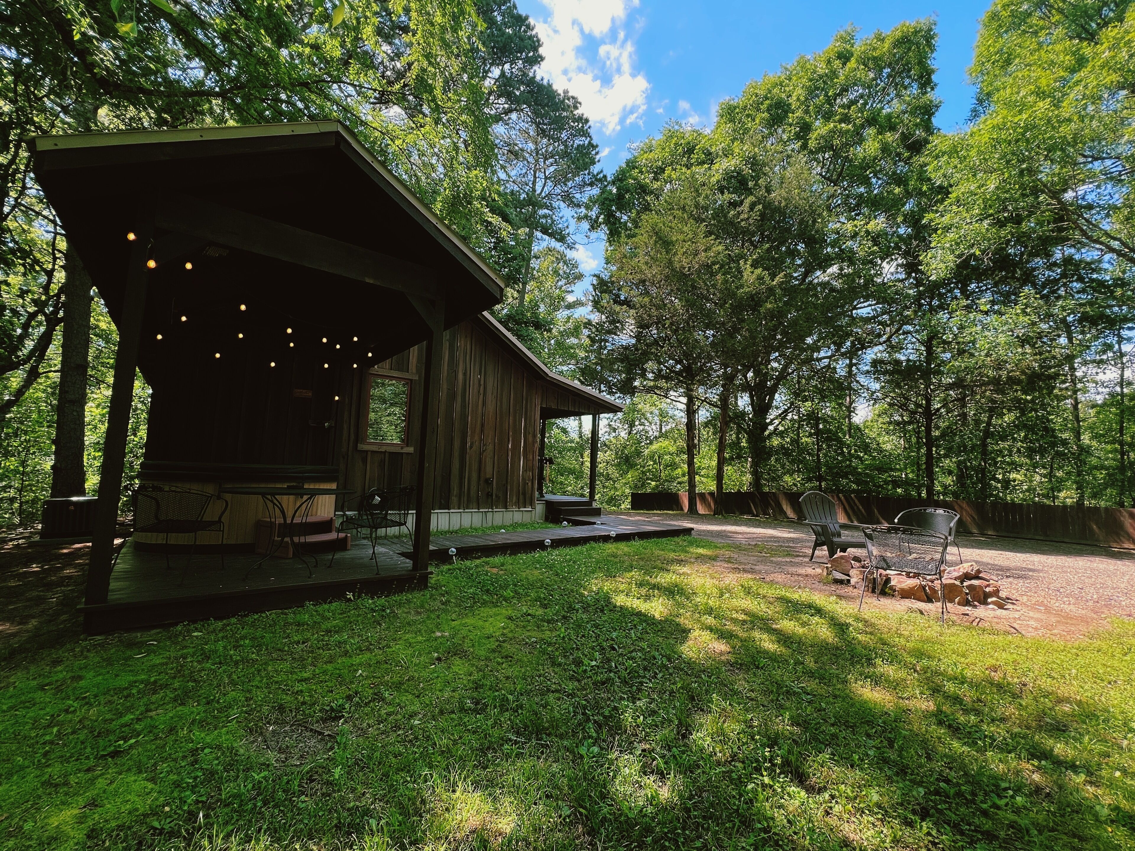 A rustic wooden cabin with an open porch, a covered seating area, and a patio with outdoor furniture.