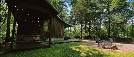 A rustic wooden cabin with an open porch, a covered seating area, and a patio with outdoor furniture.