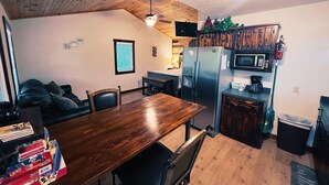 Una cucina con soffitto in legno, un tavolo da pranzo, sedie, un frigorifero, un forno a microonde e una macchina per il caffè.