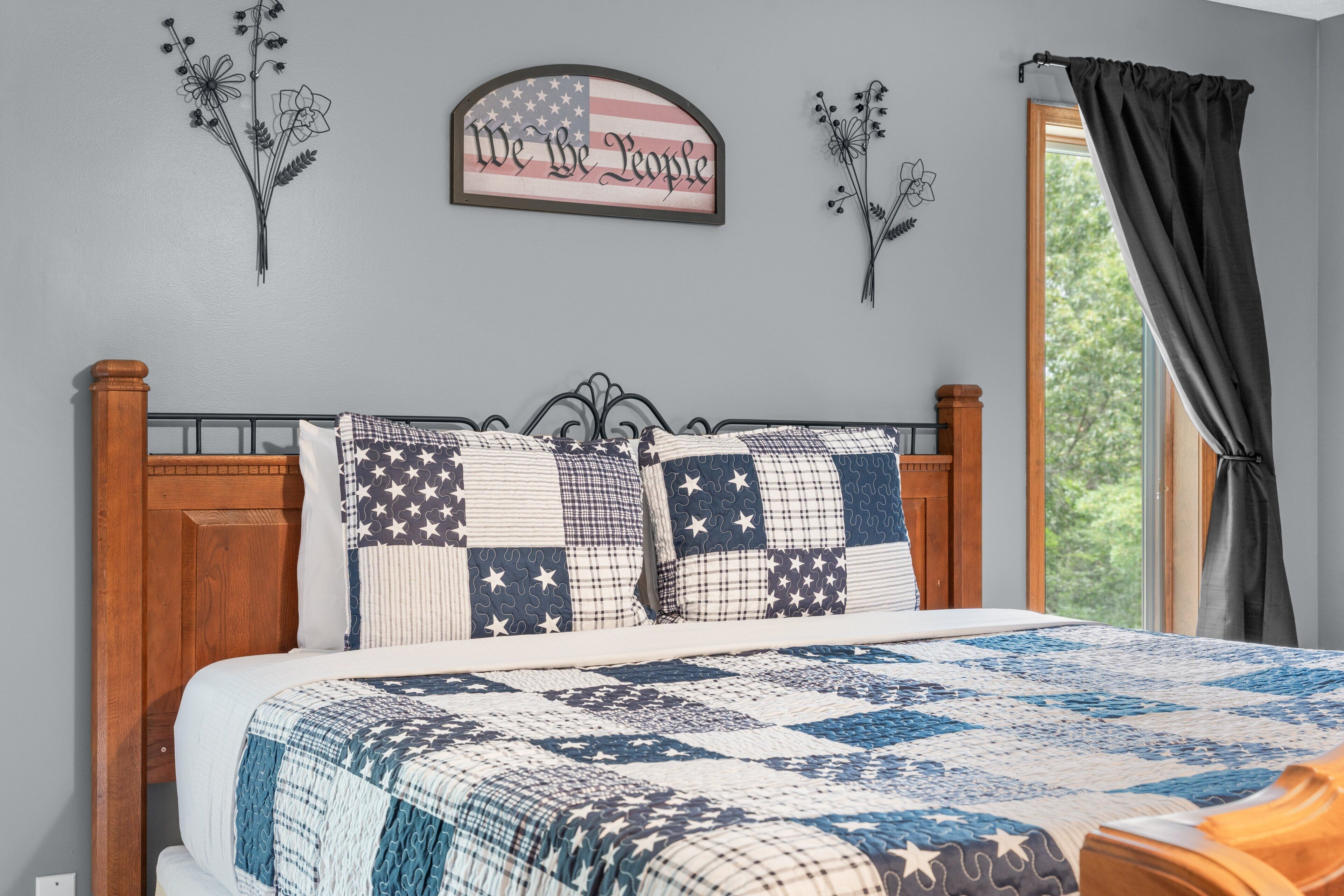 A bedroom with a wooden headboard, a quilted bedspread, and a window with a curtain.