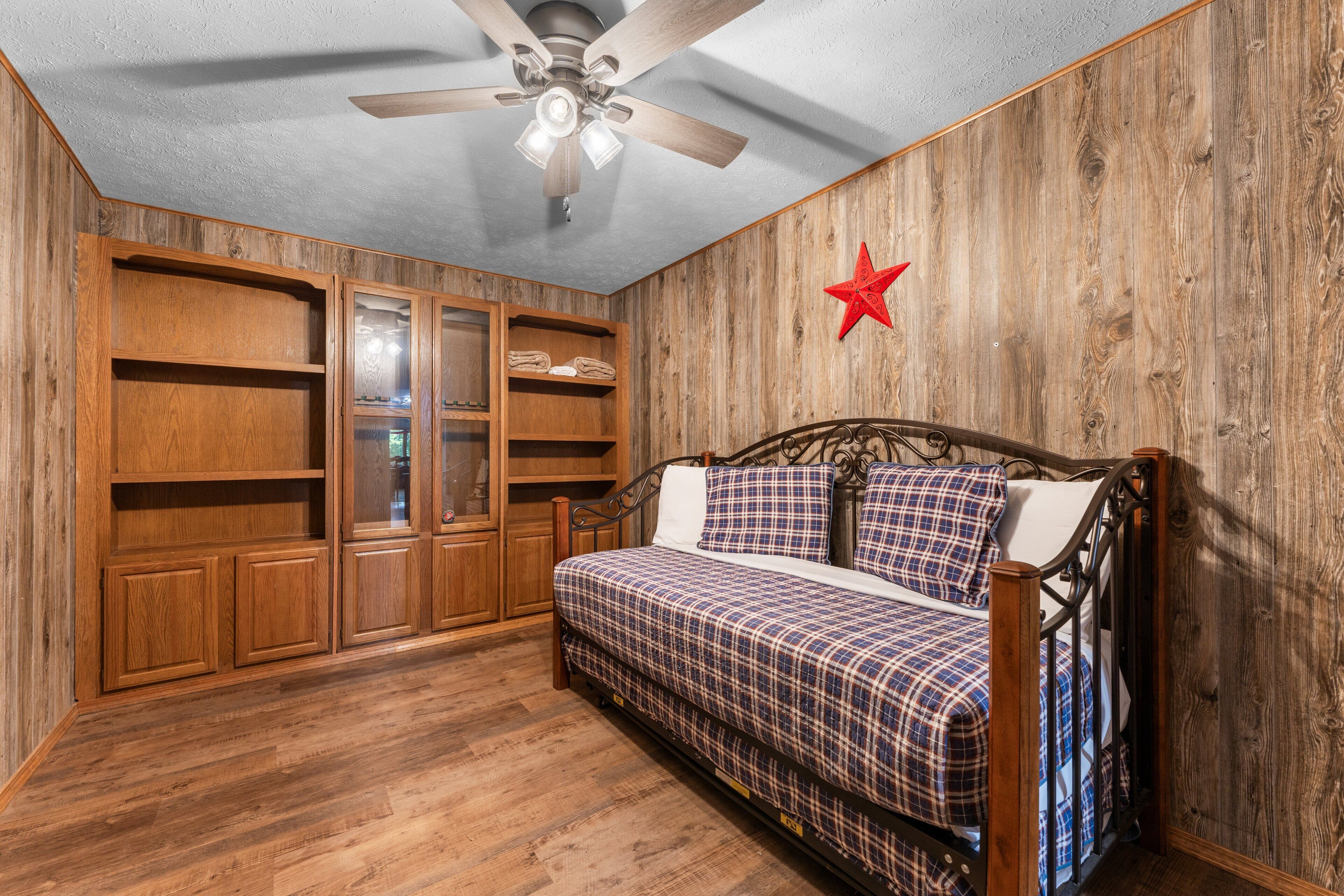 Une chambre à coucher avec un lit, une armoire en bois, un ventilateur de plafond et une décoration en forme d’étoile rouge.